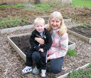 Jane Jones and her three-year-old grandson, Jaxon, in the garden area that surrounds the Coleman Avenue, Spencerport home. Jaxon loves to help his grandmother, especially with watering. Jane says the boxes are great because they are convenient and you can grow in areas with poor soil by filling the boxes with compost and organic material.