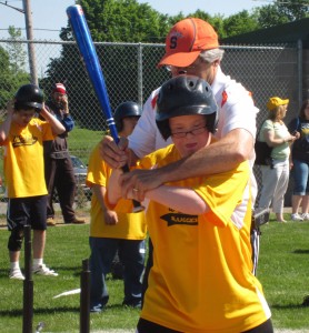 Coach Charlie Hage sets up Westside Challenger Baseball player Jake Noyes.