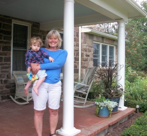 Denise Bedard on her porch holding 15-month old grandson, Beckett who already enjoys the garden.