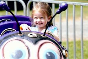 McKinley Curran, Fairport, 3, looks very happy to be driving her car in the Bees ride at the Hilton Fire Department Carnival. McKinley’s grandmother is Laurie Curran of Hilton. Photograph by Walter Horylev.