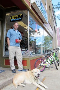 Russell Church outside his shop on Main Street in Brockport with “Sprocket.” Church and two residents recently donated new bikes for the bike loan rack at the Brockport Welcome Center. K. Gabalski photo.
