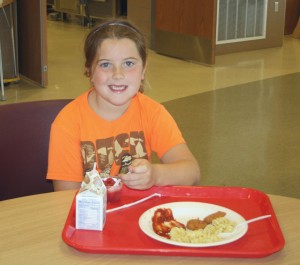 Kylee Dann enjoying a full lunch with chocolate milk, pasta, and chicken nuggets - topped off with a fruit cup for dessert.