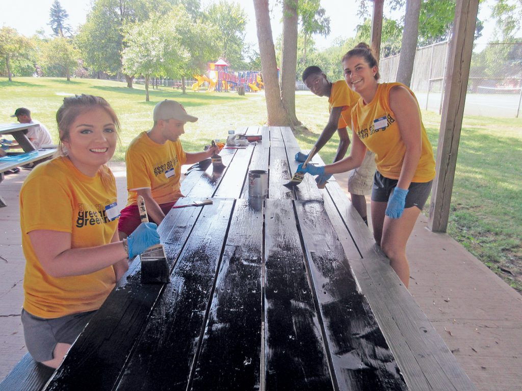 Students from the College at Brockport paint park picnic tables as part of the school’s annual Saturday Day of Service. Provided photo