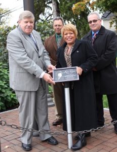 Gary Penders installs the Joyce Lobene plaque with the help of Mary, Jim and Mike Lobene. Photo by Maggie Fitzgibbon
