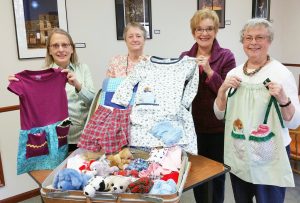 Displayed at The Center are typical items delivered locally and abroad by “Brockport Dresses for Girls Around the World.” The items include: Handmade dolls, Beanie Babies, and slippers. Also shown are a sample tee shirt dress, quilt, boxer shorts, flannel nightgown, and pillow case dress. Project workers pictured are (l to r): Mary Lynne Turner, Marcia Rachow, Kathy Mantel and Andrea Perry. Photo by Dianne Hickerson