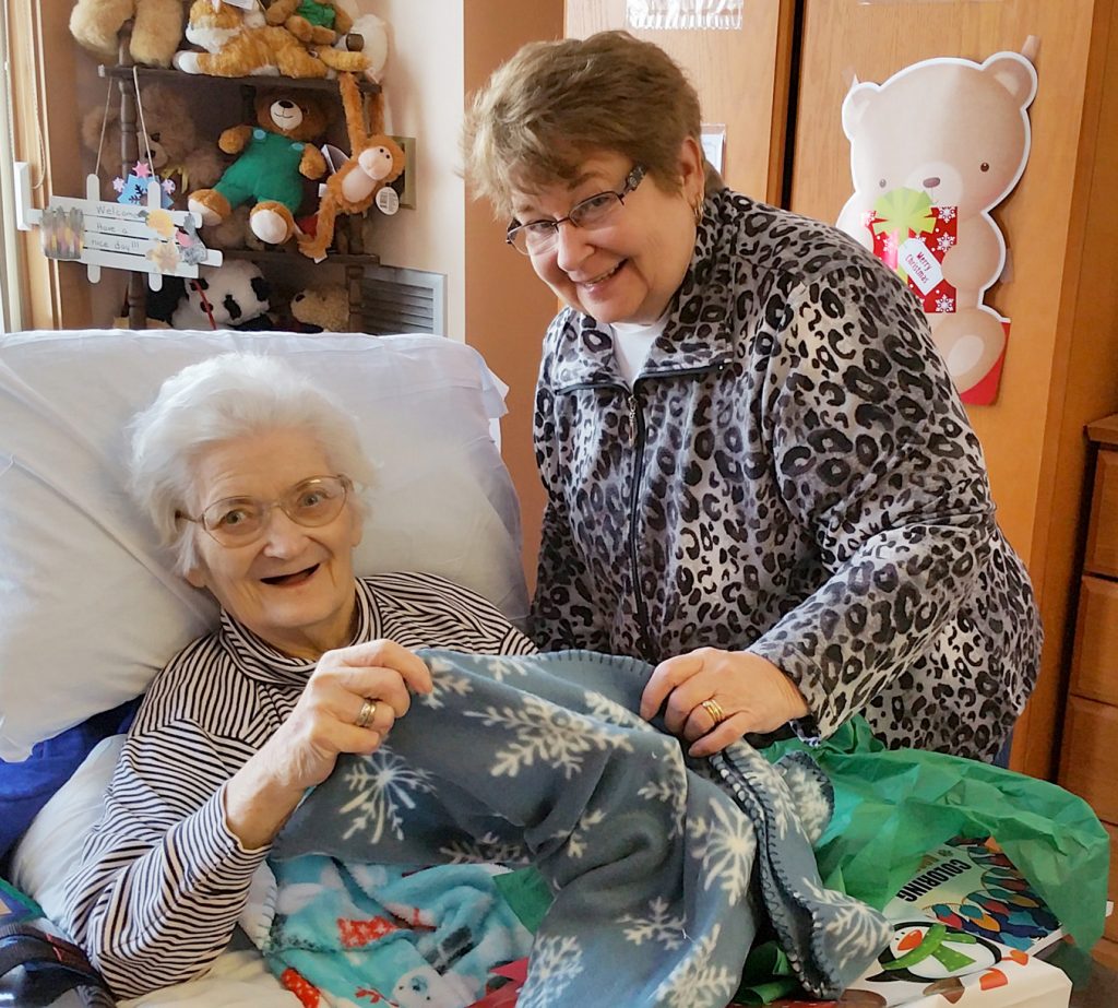 Beikirch resident Mary Ellen Frawley (left) was delighted to receive her Christmas gift, a beautiful cozy blanket, from the volunteers of the Brockport Auxiliary Service Corporation (BASC).  Her daughter Patti Frawley (right) was there to share in the festivities. Photo by Dianne Hickerson