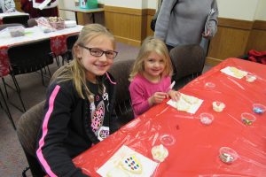 Nine-year old Addison and four-year old Alexis Staskiewicz of Brockport decorate festive holiday cookies at Seymour Library during the Strong West community holiday party. K. Gabalski photo