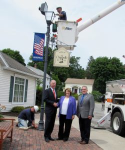 New York State Senator Mike Ranzenhofer (left) poses with Churchville Mayor Nancy Steedman and Monroe County Legislator Steve Brew on Wednesday, July 26, outside the Churchville Village offices. Linemen from Churchville Municipal Electric have been upgrading decorative lighting in the business district with LED fixtures thanks to a state grant secured by Senator Ranzenhofer. K. Gabalski photo