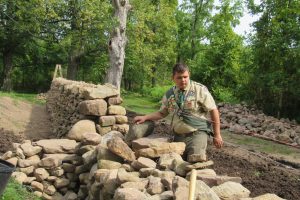  Eagle Scout Donovan Berbeneciuc inspects the south end of the stone wall at the Colby/Pulver House. He says he received numerous “granite kisses” - pinched fingers and hands - during construction of the wall for his Eagle Scout project. K. Gabalski photo