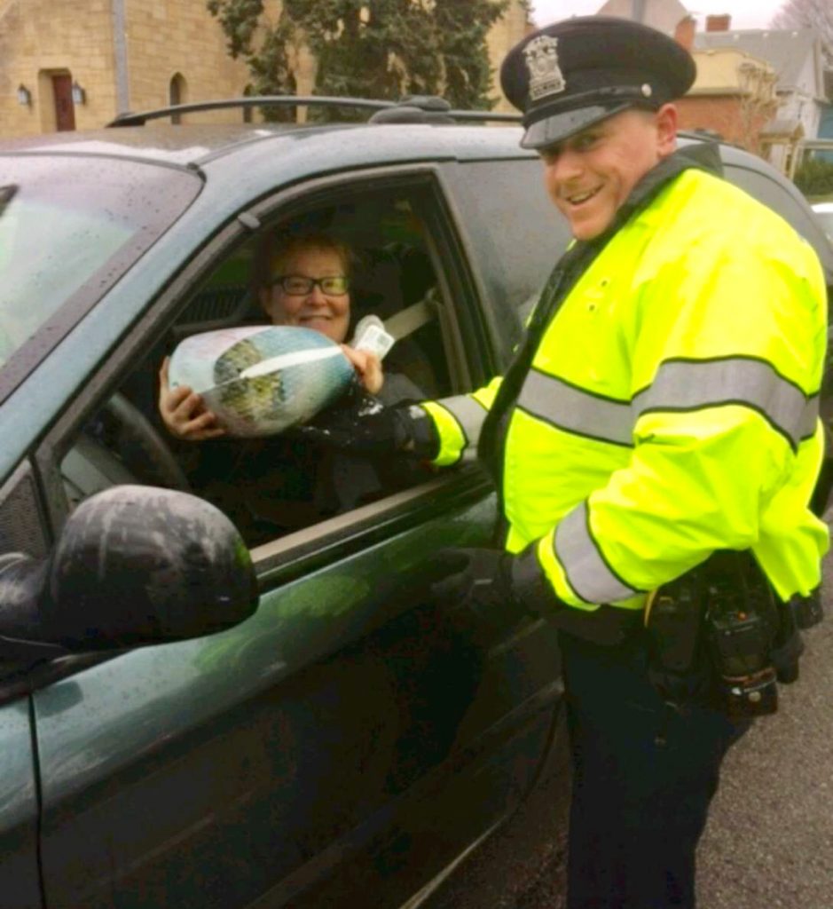 Officer Vadas of the Brockport Police Department giving away a frozen turkey to a motorist at a safety check point in the village.