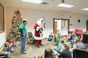 Santa visits with children during the annual “Umpteenth” holiday party in Clarkson. Supervisor Paul Kimball looks on.