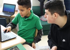 A second-grader at Fairbanks Road School shares his research and online presentation on artic mammals with a visiting high school student. Provided photo
