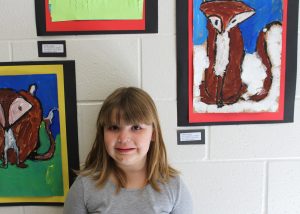 First-grade artist Kathryn Uzialko with her painting of a fox (top, right) at Churchville-Elementary’s art show.