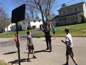 Officer Sims, while out on patrol, stops to interact and shoot hoops with Brockport youth. Provided photo