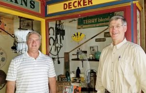 Doug Bull (left) and Bruce Newell stand in front of two of the four historic Brockport store fronts they created in the Emily L. Knapp Museum. Shown here in partial view are Fagan’s Clothing Store and Decker Hardware. Sue Savard arranged the display windows with artifacts from the museum. Photo by Dianne Hickerson
