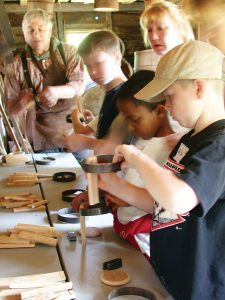 Youngsters try their hand at assembling small buckets under the watchful eye of Genesee Country Village & Museum cooper Jerry Walter.
