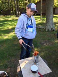 Owen from Monroe County 4-H learns to start a fire to use his outdoor cooking skills.