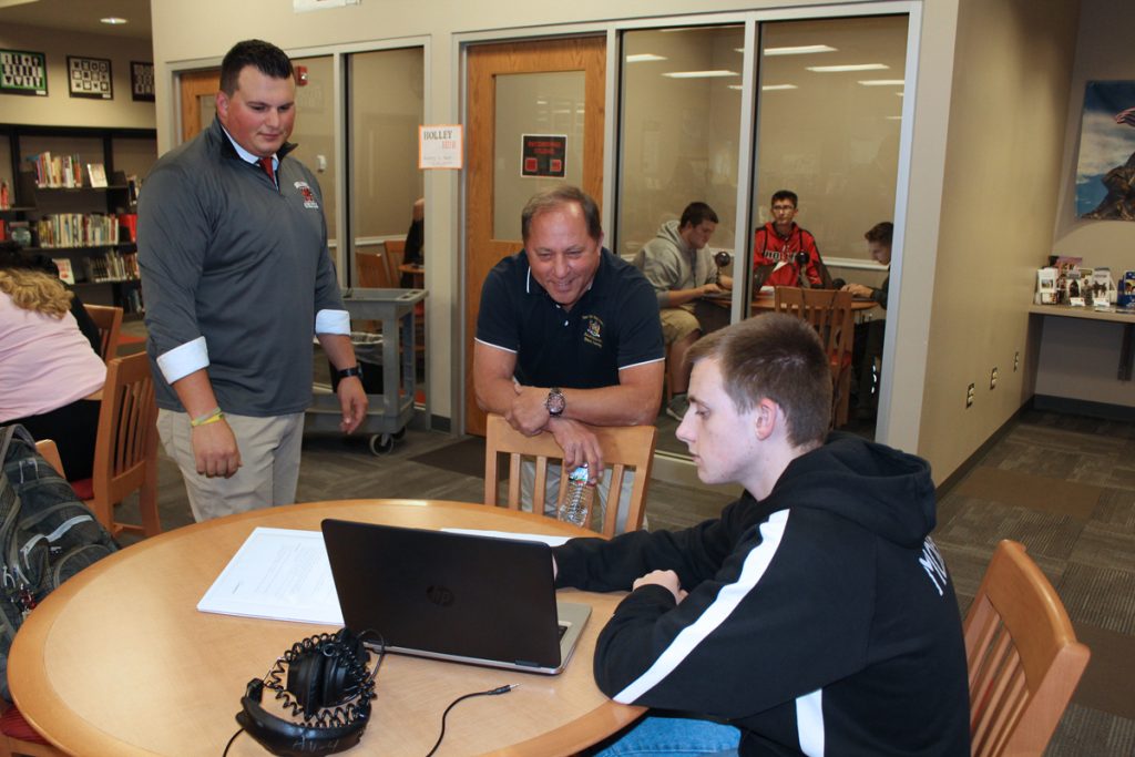 From left, Current Events teacher Nick D’Amuro and Assemblyman Hawley listen to student Greg Morrill explain editing the podcast.