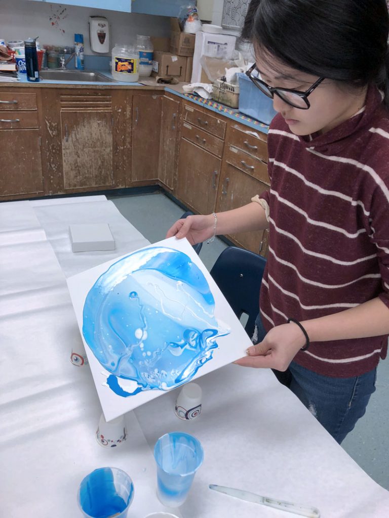 Student performing acrylic pour painting technique. Photo by Sandy Auer
