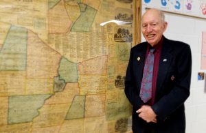 Bill Andrews stands next to an 1858 Monroe County map, one of many maps on display in the second-floor hallway of Hill School. Photo by Dianne Hickerson