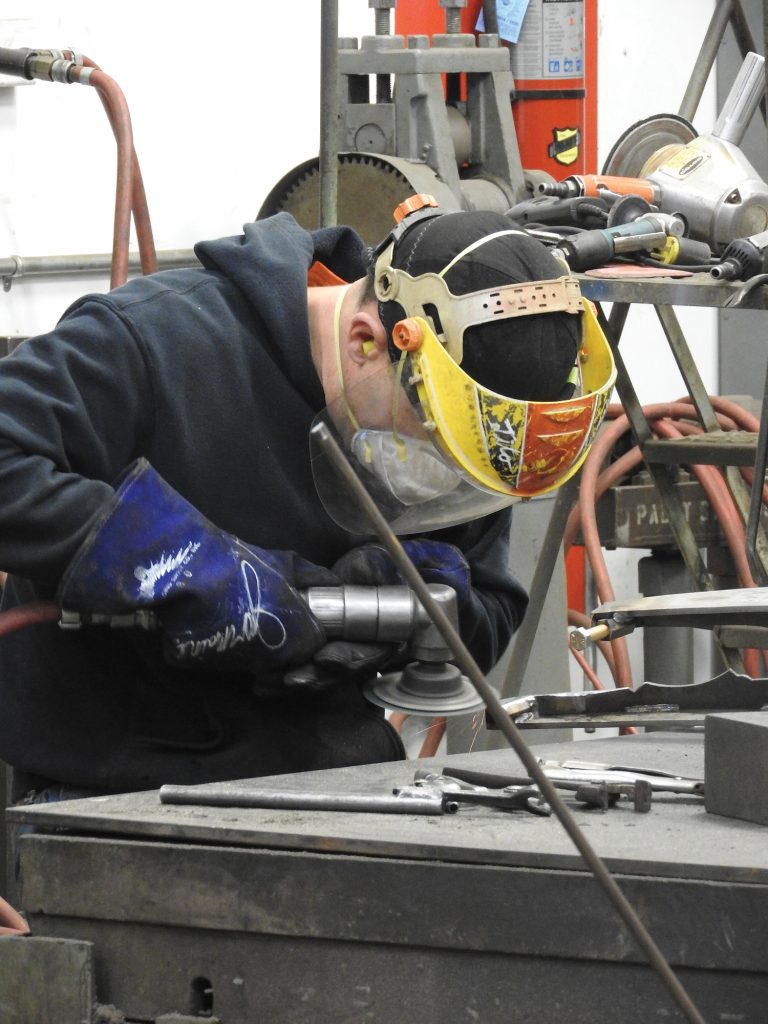 Worker in fabrication studio using a grinder.
