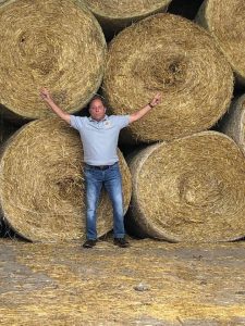 Hawley poses next to giant hay bales at Zuber Farms in Churchville, where the owners produce corn, hay, wheat and dairy replacements. 