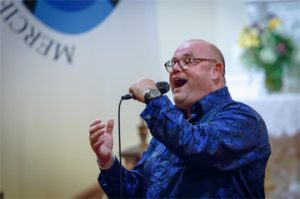 Ronan Tynan – one of the great tenor voices in the world – is returning to Medina. Tynan will perform at 7:30 p.m. on Saturday, October 5, at historic St. Mary RC Church, once again presented by the Orleans Renaissance Group, Inc. While widely known as a world-class tenor, Tynan is a much more complex and fascinating individual. His life story is as varied as the seasons, full of both tragedy and inspiring triumphs. Ronan Tynan has performed at many celebrated and historic events around the world – President Reagan’s funeral as well as the inauguration and funeral of President George H.W. Bush. His booming voice has echoed out in St. Patrick’s Cathedral, Carnegie Hall and the Washington National Cathedral; across the National Mall and at St. Peter’s Basilica at the Vatican for Pope John Paul II and Pope Benedict. Despite this incredible fame, few know the rest of his remarkable story – he is a medical doctor, Paralympian, recording artist, motivational speaker, and more. Often, it is the sum total of his life experiences that allows him to connect and bond with an audience like few other performers. Born on a farm in County Kilkenny, Ireland, Tynan was born with lower leg deformities. Despite this setback, his parents always encouraged him to do anything he wanted to do. His drive and motivation comes from the loving environment in which he was raised. His parents never let his disability stand in his way. He attended an all-boys boarding school and vigorously competed in athletic activities. A motorcycle accident at age 21 claimed both Tynan’s legs below the knee, but out of this apparent tragedy came great triumph. He went on to compete as a double amputee and win 18 gold medals and set 14 world records in the Paralympics Games from 1981 to 1984. If that were not enough, he studied medicine and became a medical doctor, specializing in orthopedic sports medicine. By the time he pondered singing, his life was already one of incredible accomplishment. When he was 30 years old, Tynan began to study voice while still in medical school. The year was 1993, and he was in his fifth year of medical school. By 1998, after establishing himself as an award-winning tenor, Dr. Tynan had joined Irish tenors Anthony Kearns and Finbar Wright and went on to legendary fame across the globe. Audiences the world over flocked to hear this trio. However, after six years, Tynan left the group to begin his solo career. Today, Tynan continues with his career, entertaining sold-out audiences in churches, theaters and concert halls around the globe. He is one of the most sought after motivational speakers in the U.S., presenting nearly 50 speeches annually for major international corporations and organizations. Before his appearance in Medina this October, Tynan will perform in New Orleans and shortly thereafter in Boston. “The 2016 concert was one of the most incredible events I have ever witnessed, most certainly in Medina,” said Chris Busch, President of ORG. “He’s a warm and friendly man – very kind and genuine. He has enormous presence. It is quite true what has been said about his ability to connect with an audience – never have I seen an audience so thrilled and so moved. I’ve attended many concert events in my life, but experiencing Ronan Tynan is very special.” At that concert event, Tynan delighted a capacity crowd of over 600 fans, many of whom traveled to Medina from across western New York and around the United States. Tynan performed for three hours, captivating the audience with his voice, his humor and personal stories of his life growing up in Ireland.  One of the highlights of the evening in 2016 came as Tynan recalled a story of how he came to sing “Over the Rainbow” at a military event, honoring several Vietnam veterans. One of the vets – a retired colonel and Medal of Honor recipient – recounted how that very song inspired him and his men throughout the conflict and helped bring everyone home alive. Tynan dedicated the song to all military personnel and first responders and recognized any present in the audience. The emotionally charged performance brought the crowd to their feet with thunderous applause. “Tickets are selling quickly,” said Busch. “If you have any thought of attending this event, do not hesitate to purchase your tickets now. It will sell out. This is your chance to experience a concert event of a lifetime in a truly magnificent setting.” Tickets are $45 each ($50 at the door) and are available at online medinaalive.com. All seats are general admission. Doors open at 7 p.m. There are a limited number of specially-priced, premium front-row seats available. For premium seat information, call 590-0699. 