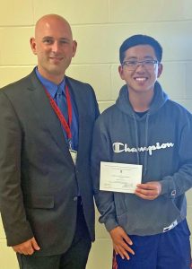 Dr. Jeffrey Green, Hilton High School principal, presents senior Brian Phung with a Letter of Commendation from the National Merit Scholarship Corporation.