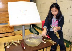 Sara Bishop, an intermediate student at Quest Elementary School in Hilton, makes corn husk dolls during Quest Feast.