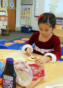 Ava Tran carefully prepares a peanut butter and jelly sandwich for the Open Door Mission. 