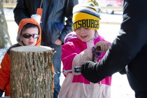 Visitors get hands-on experience with tools of maple collecting. Photo by Melody Burri 