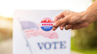 Hand showing I voted today badge at ballot box at american elections.