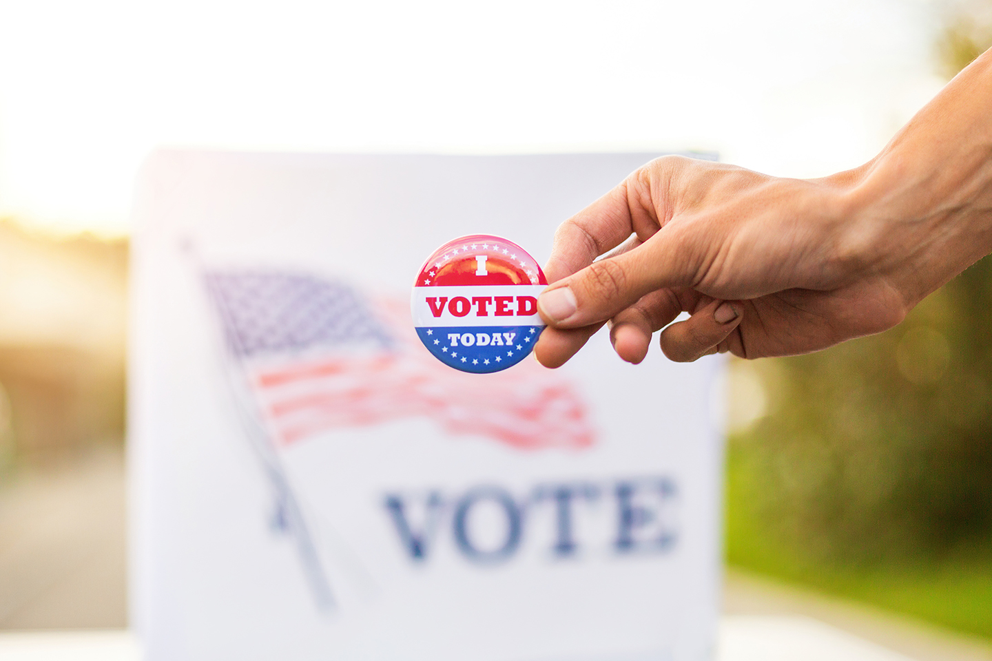 Hand showing I voted today badge at ballot box at american elections.